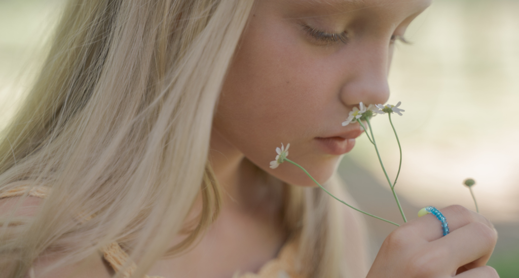 Ein Mädchen riecht an einer Blume.