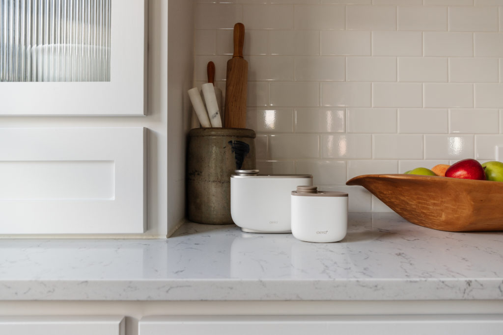 Der AERA Smart und der AERA Mini stehen neben einer Obstschale auf einer Küchenzeile.